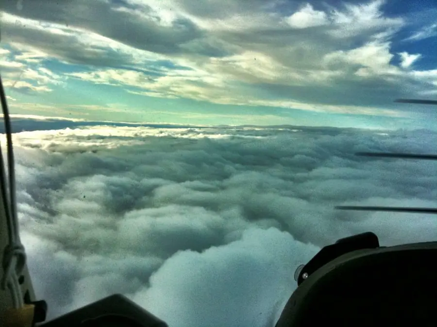 Above the clouds from a small plane, with the wing strut in view
