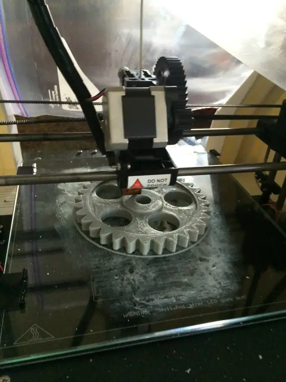A 3D printer halfway through printing a gear